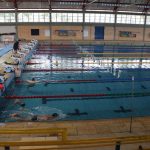 foto da piscina olímpica da UFSC, com sete alunos na água. Um aluno nada, enquanto os outros olham para o professor