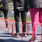 pernas de três alunos de atletismo, que passam por cima de obstáculos à altura do joelho