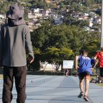 professor de atletismo Diego Antunes observa três homens correndo na pista de atletismo da UFSC